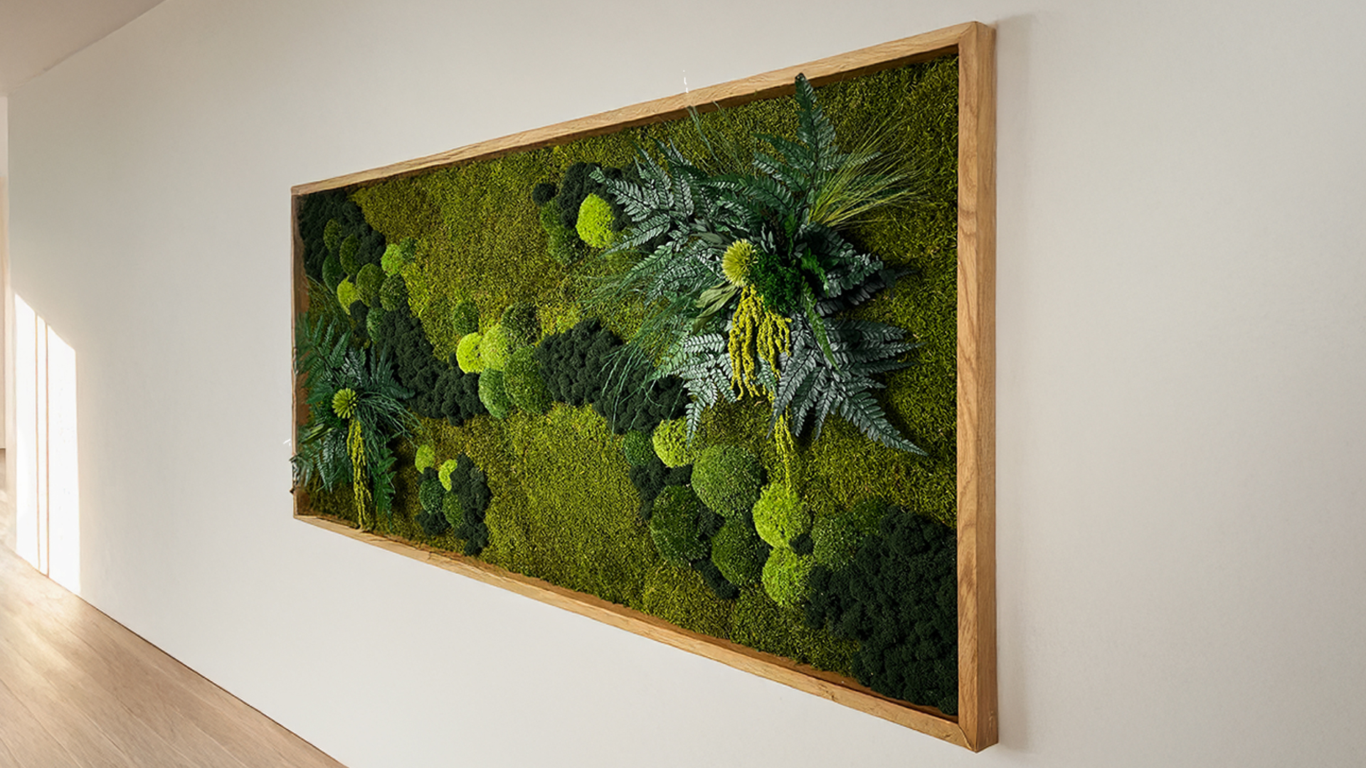 Kompozycja z mchu w drewnianej ramie zawieszona na ścianie pokoju